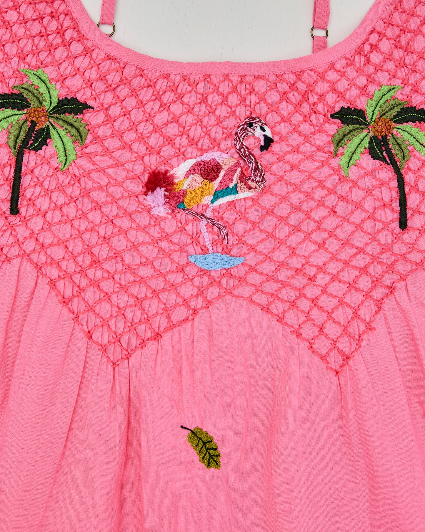 Close-up of the coral top's openwork yoke with an embroidered flamingo between two palm trees