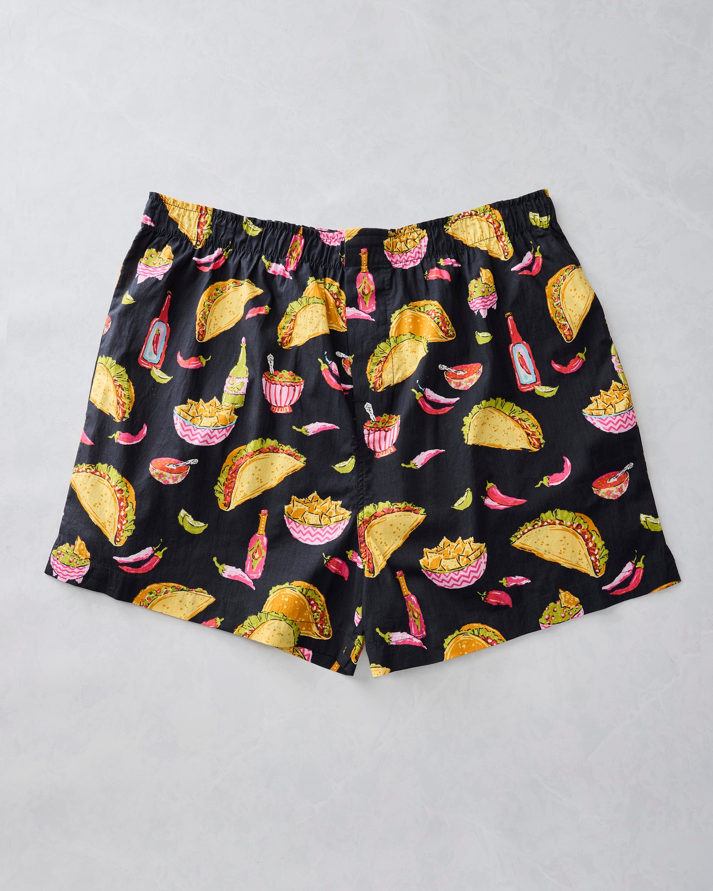 Lava Rock boxer shorts laid flat with tacos, nachos, peppers, salsa, and bottles on a black background