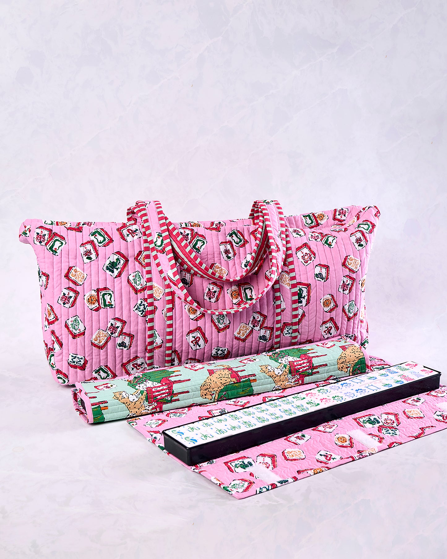 Peony pink quilted Mah Jongg bag with handles and a printed tile pattern, shown with a rolled item, game rack, and mat.