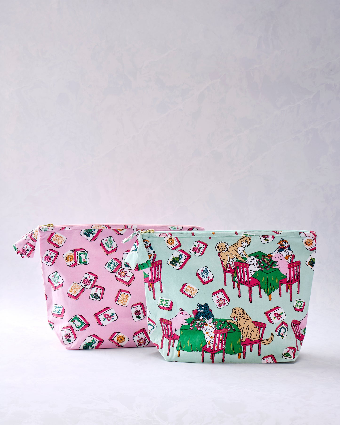 Two zip pouches, one pink with tile motifs and one mint with animals playing mah-jongg