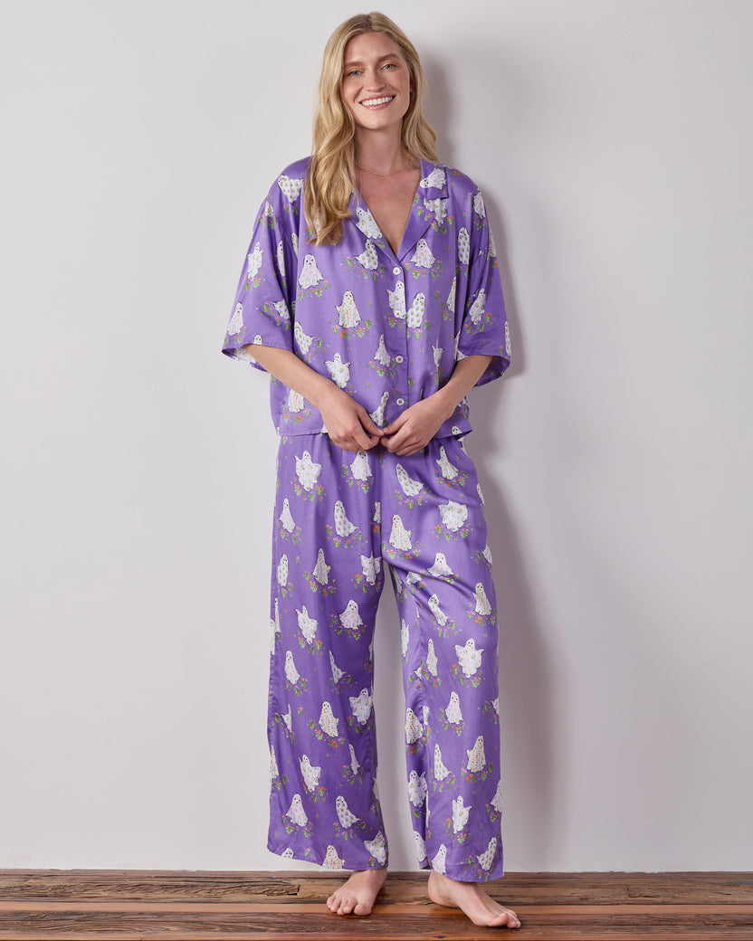 Full-length front view of the purple Gardening Ghosts pajama set with a collared button-front top and wide-leg pants in a white ghost-and-floral print.