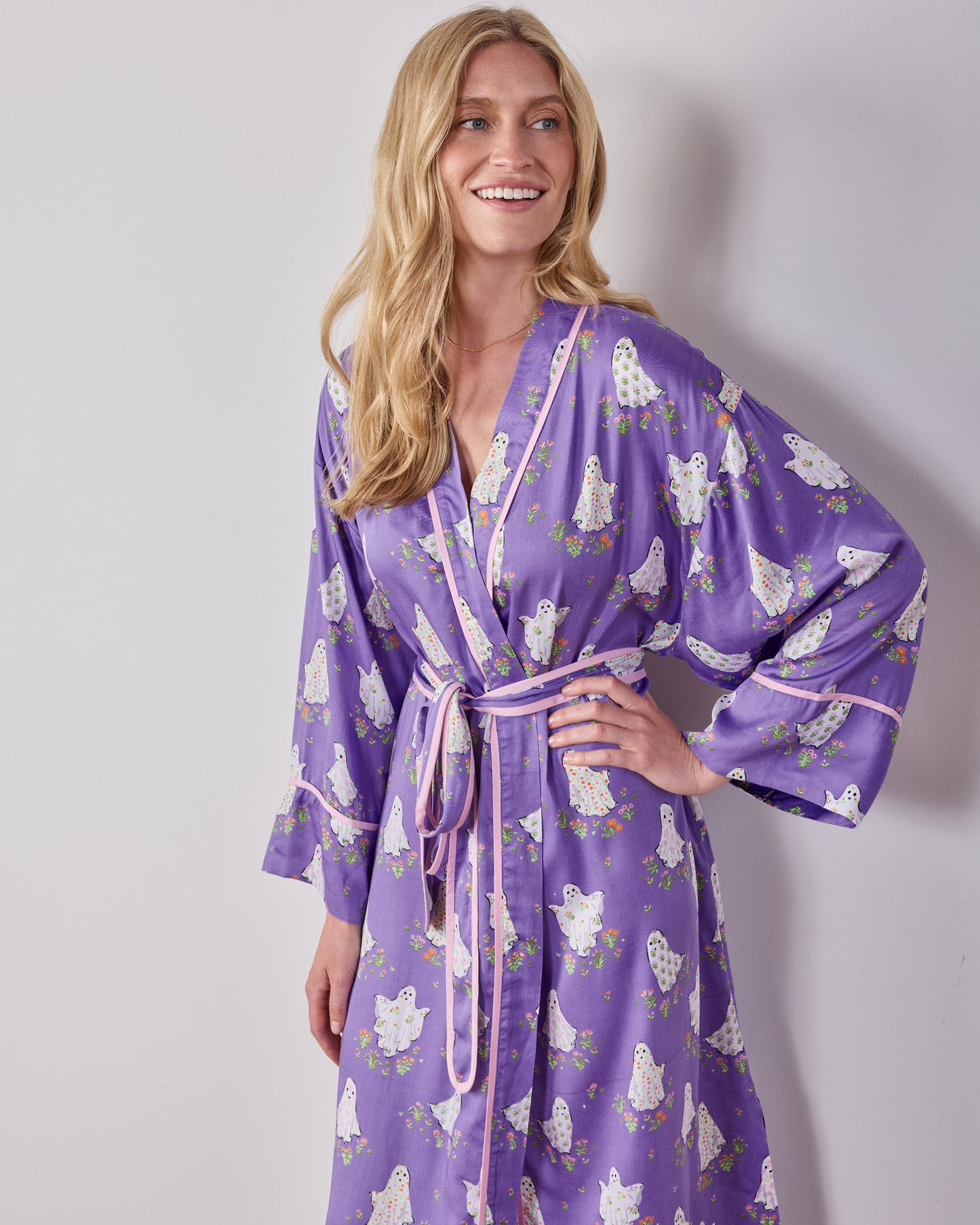 Upper-front view of the purple ghost-and-floral print robe, showing the pink-trimmed wrap front, belt, and wide sleeves.
