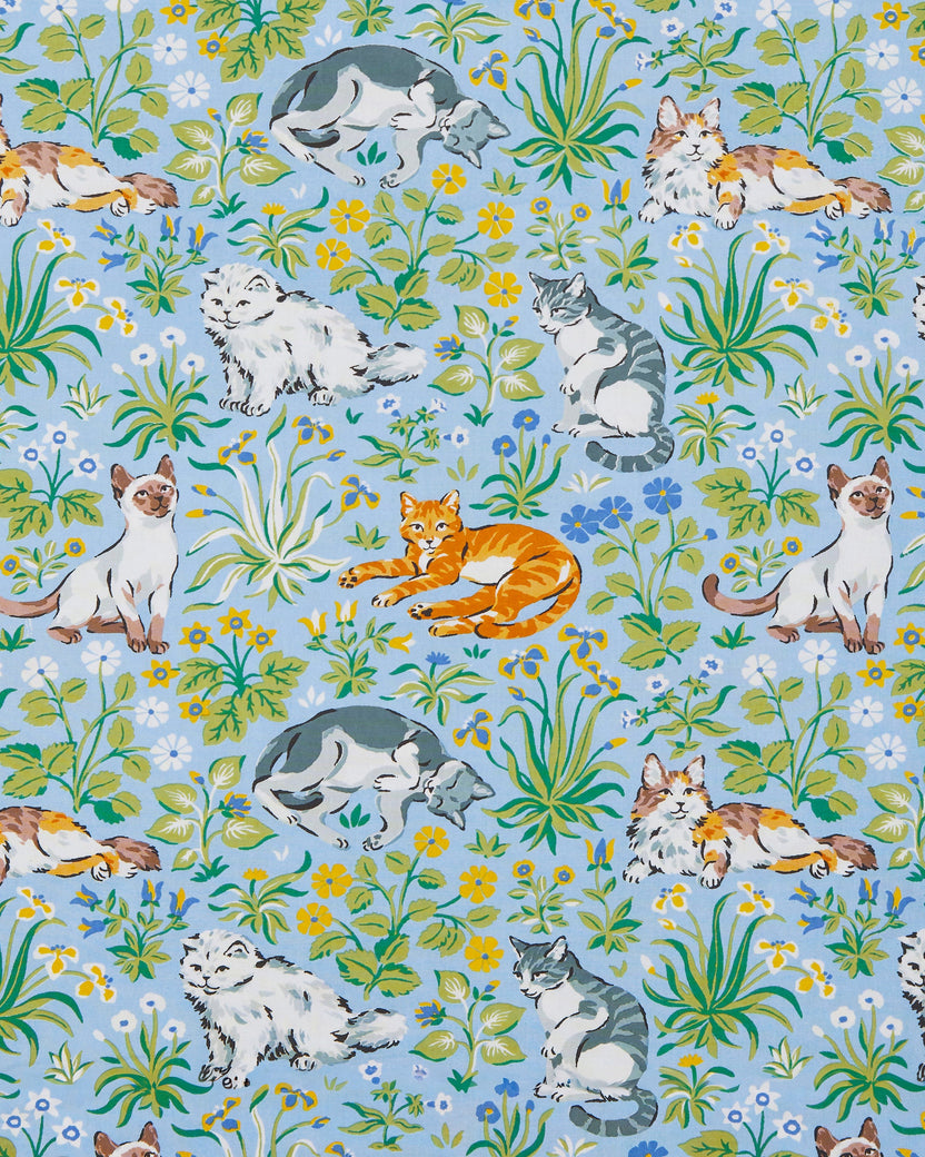 Cornflower-blue print with lounging cats among green leaves and blue, yellow, and white flowers