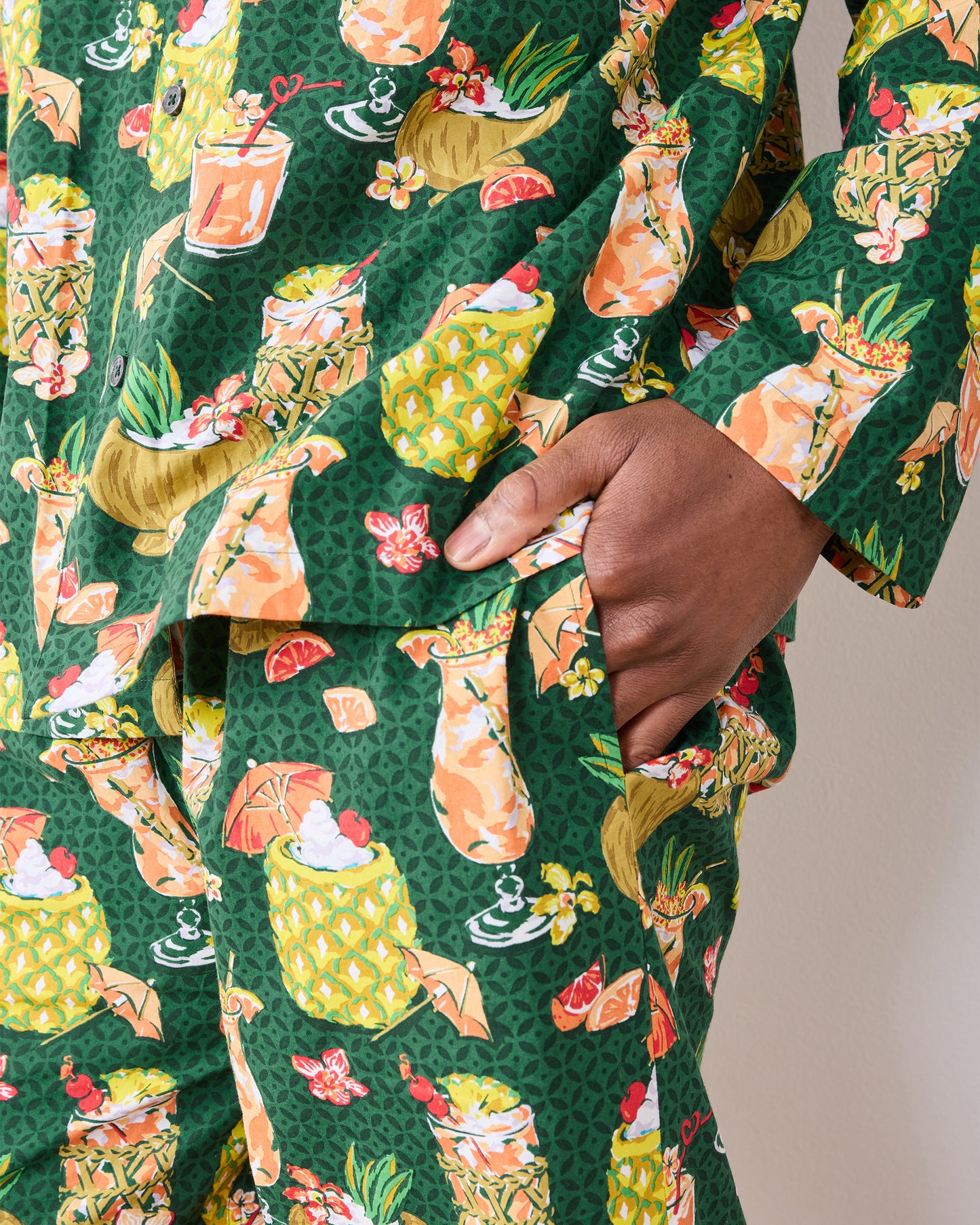 Close view of a hand inside the pajama pants pocket, showing the tropical drink print