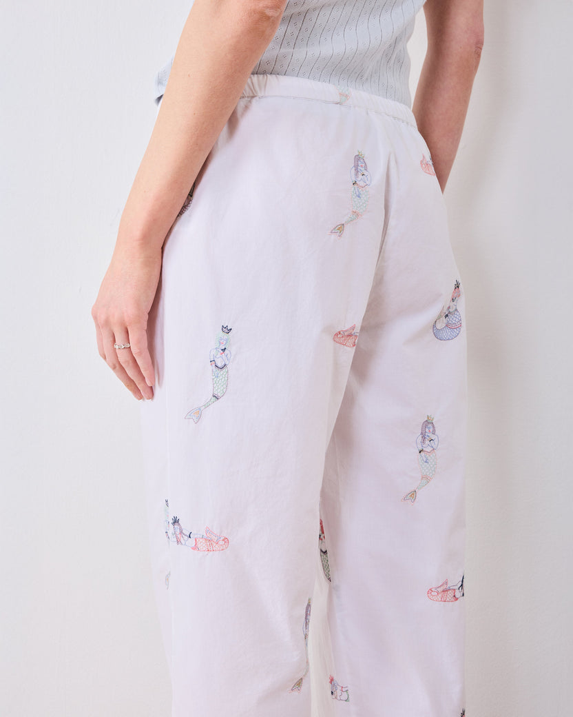 Rear close-up of white pajama pants with scattered embroidered mermaid figures and an elastic waistband