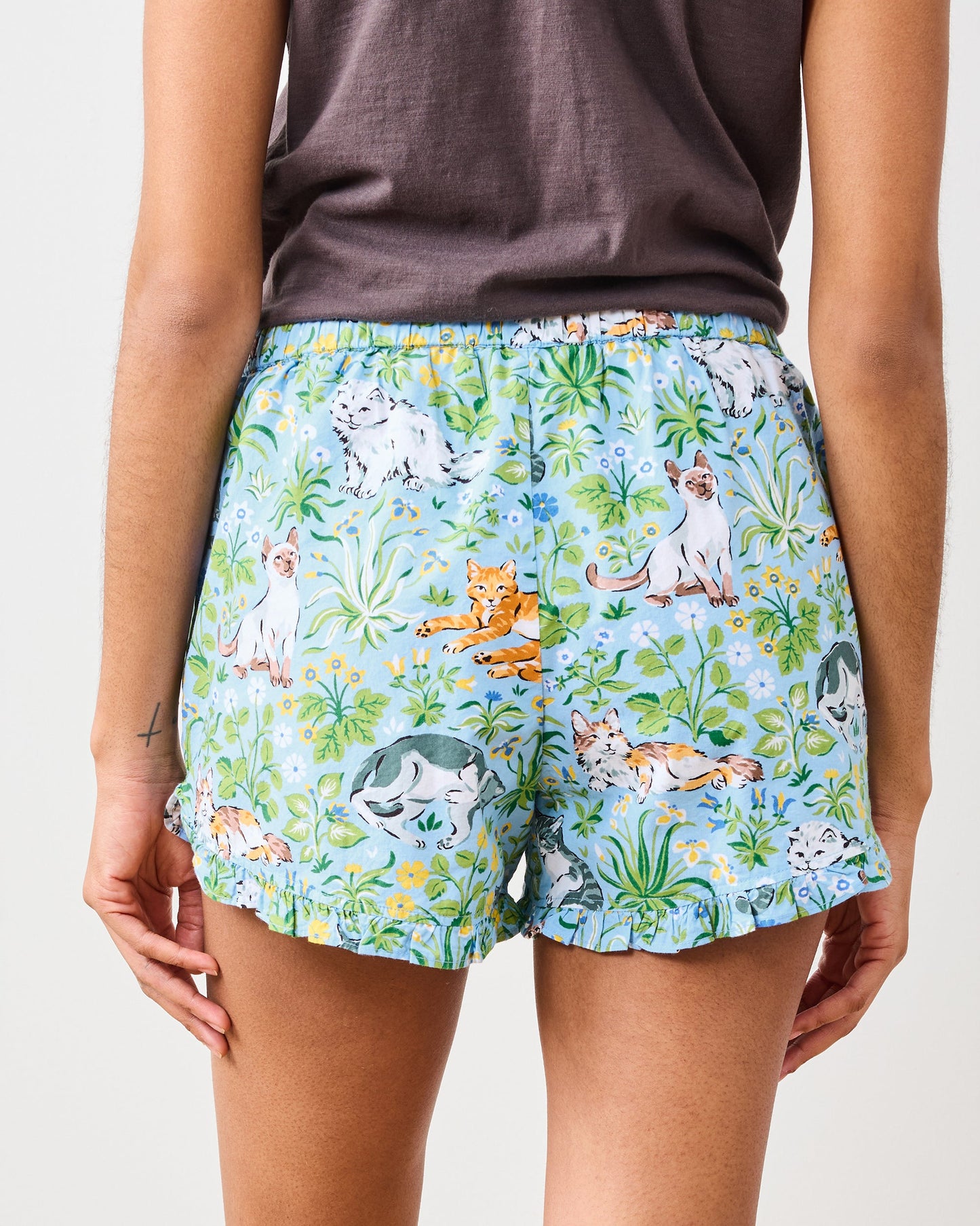 Close back view of blue cat-print shorts with an elastic waist and ruffled hems