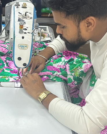Person operating an industrial sewing machine on brightly patterned fabric