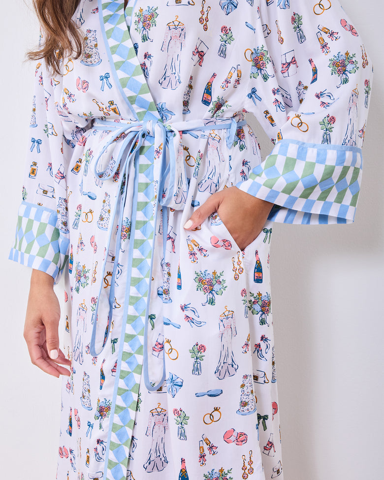 Front view of the bridal-print robe with geometric trim, tied belt, and one hand in a pocket
