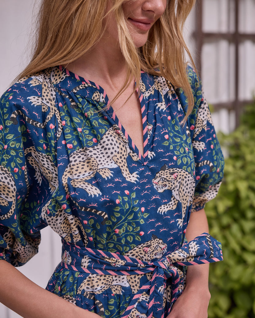 Close view of the Bagheera dress showing its V-neckline, leopard-and-floral print, puff sleeve, and tied waist belt.