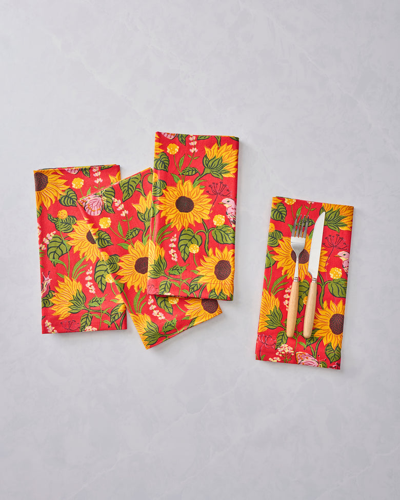Four orange patterned napkins displayed with a fork and knife on one napkin.