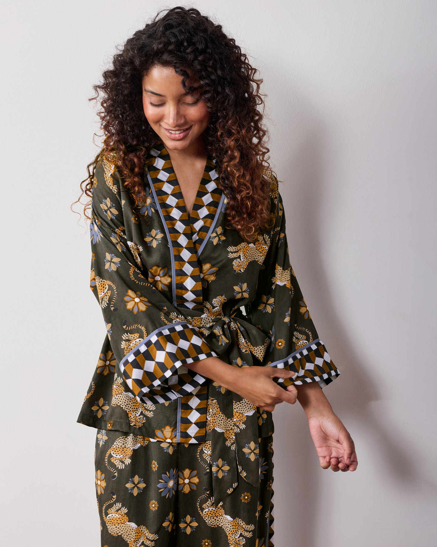 Angled front view of the olive Wrap Set with a belted wrap top, geometric trim on the neckline and cuffs, and matching printed pants.