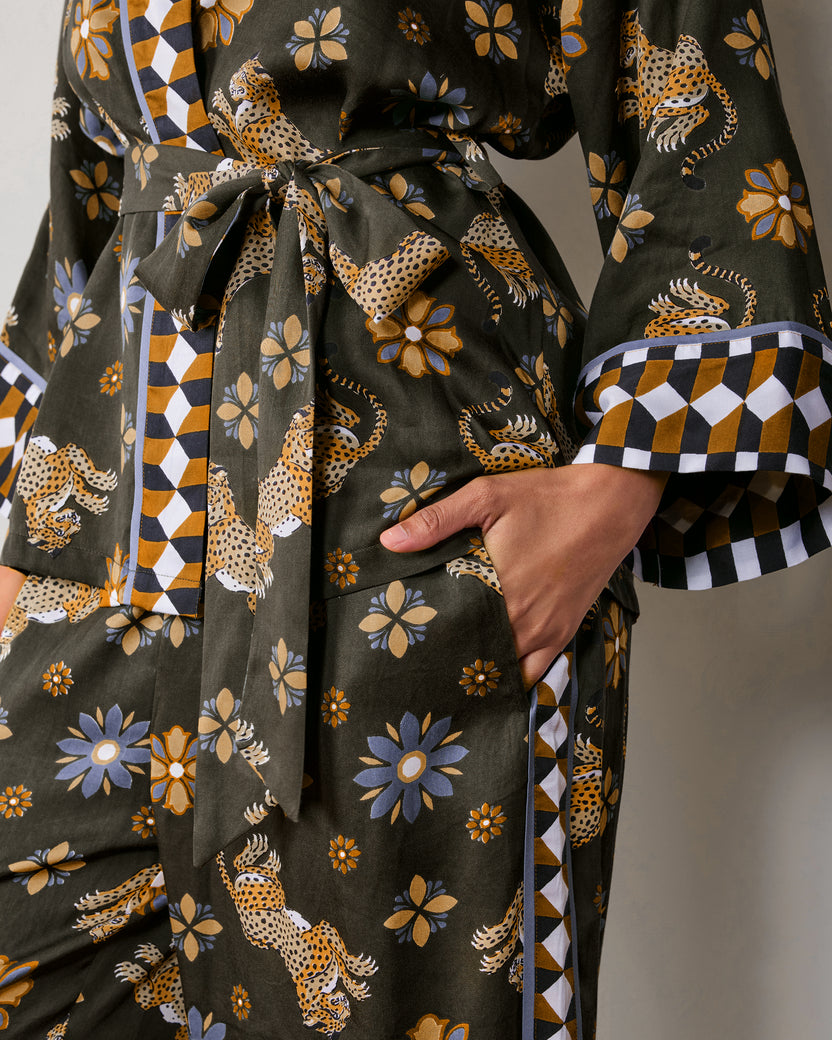 Close-up detail of the olive Wrap Set showing the tied waist, geometric-trimmed cuff, printed pants, and side pocket.