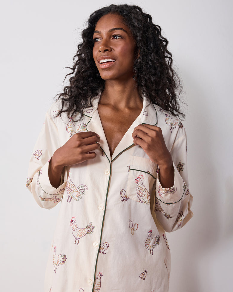 Close view of the long-sleeve pajama top with button front, piping, chest pocket, and embroidered hen pattern.