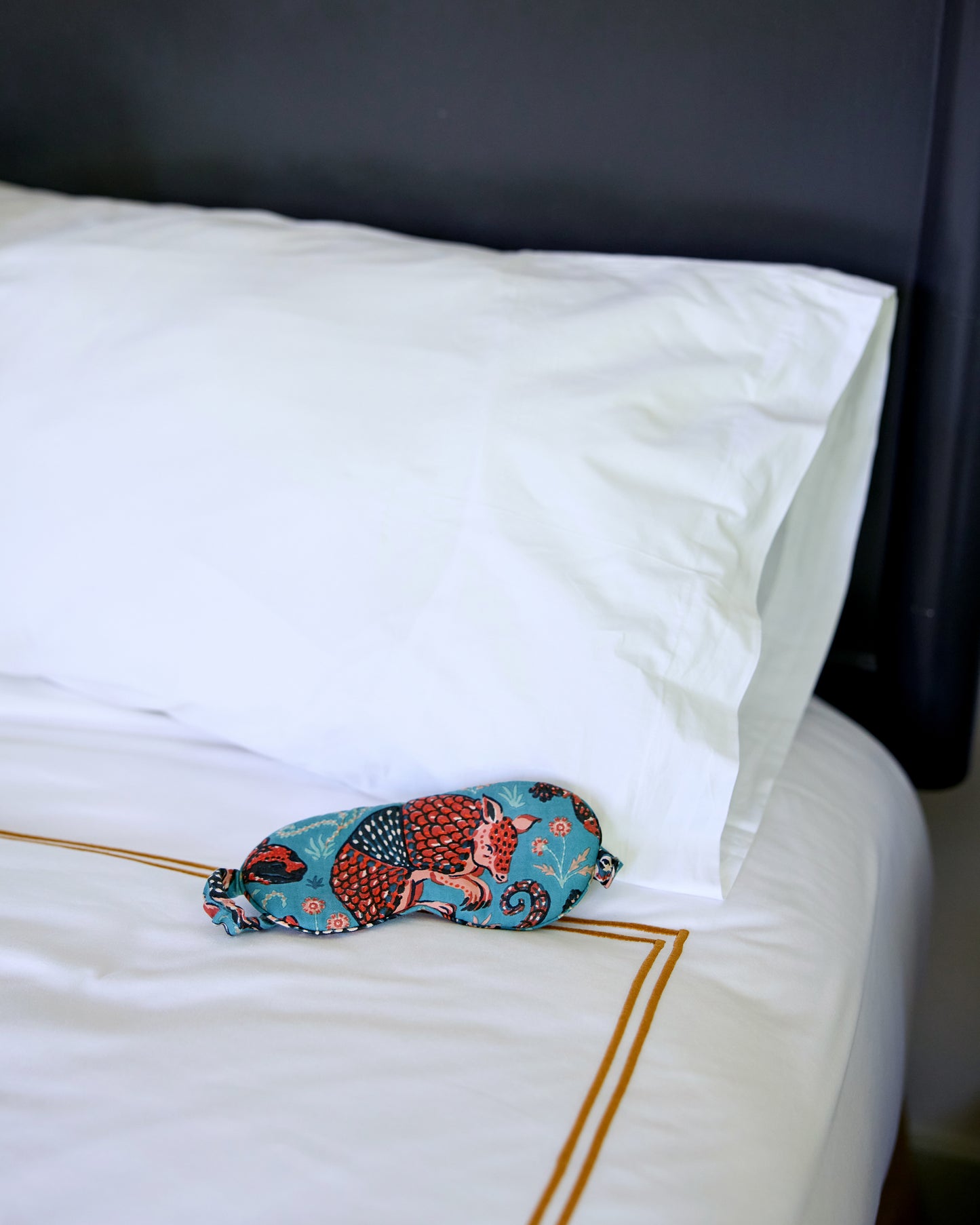 Teal Southwestern Critters eyemask resting on a white bed.