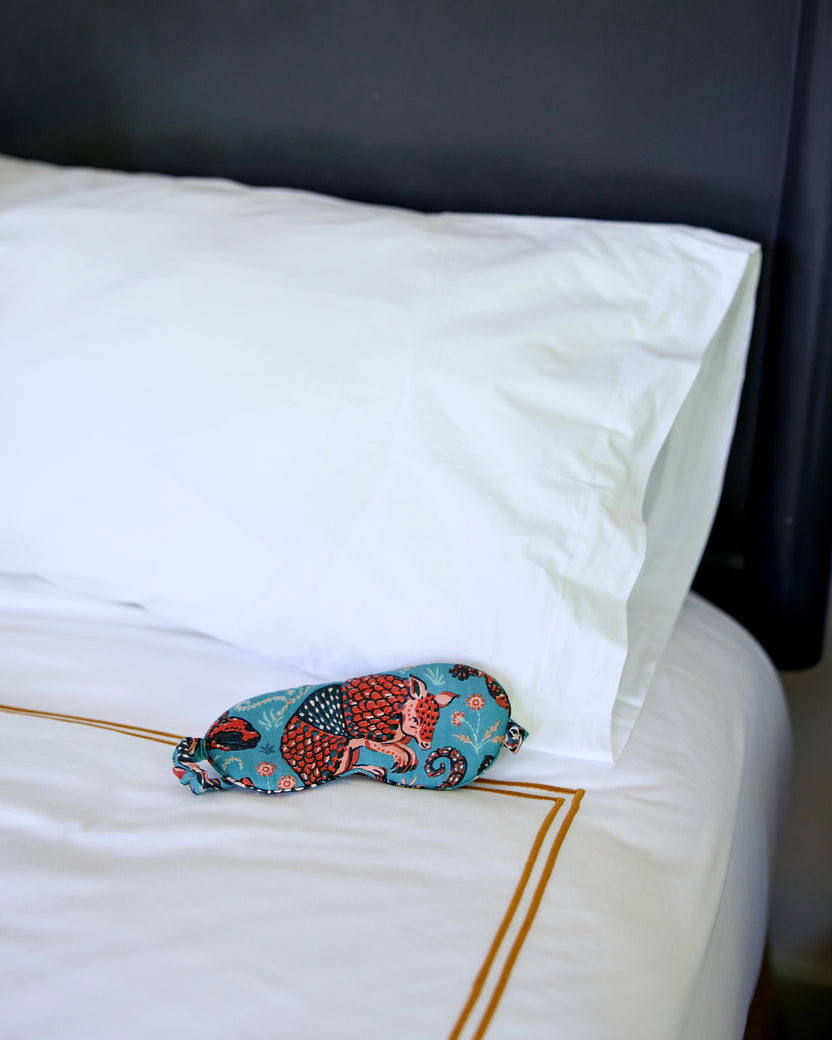 Teal Southwestern Critters eyemask resting on a white bed.