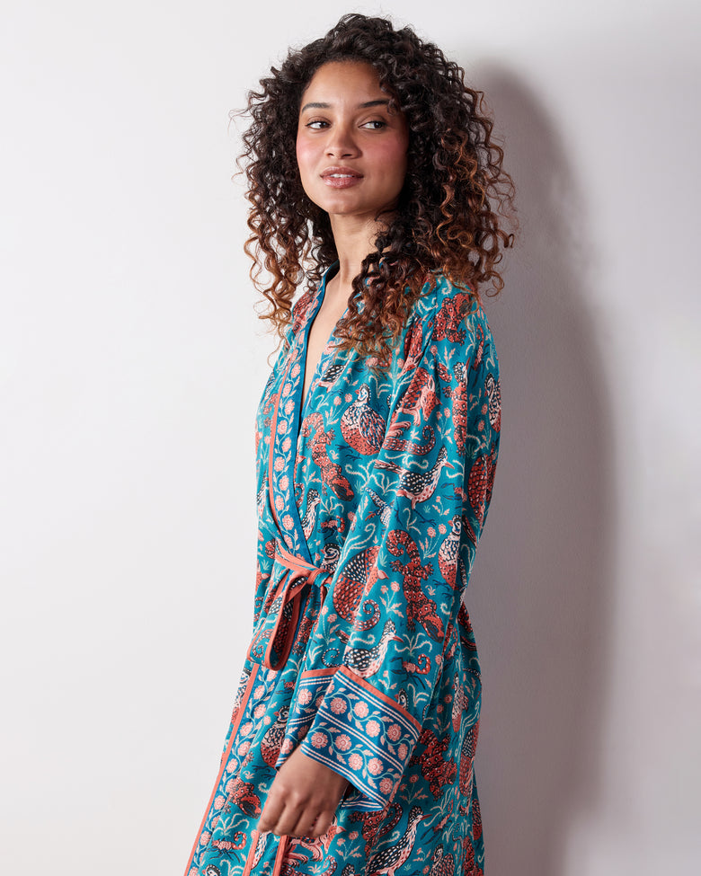Side view of the teal Southwestern Critters satin robe showing the wrap front, tie belt, wide sleeve, and patterned cuff.