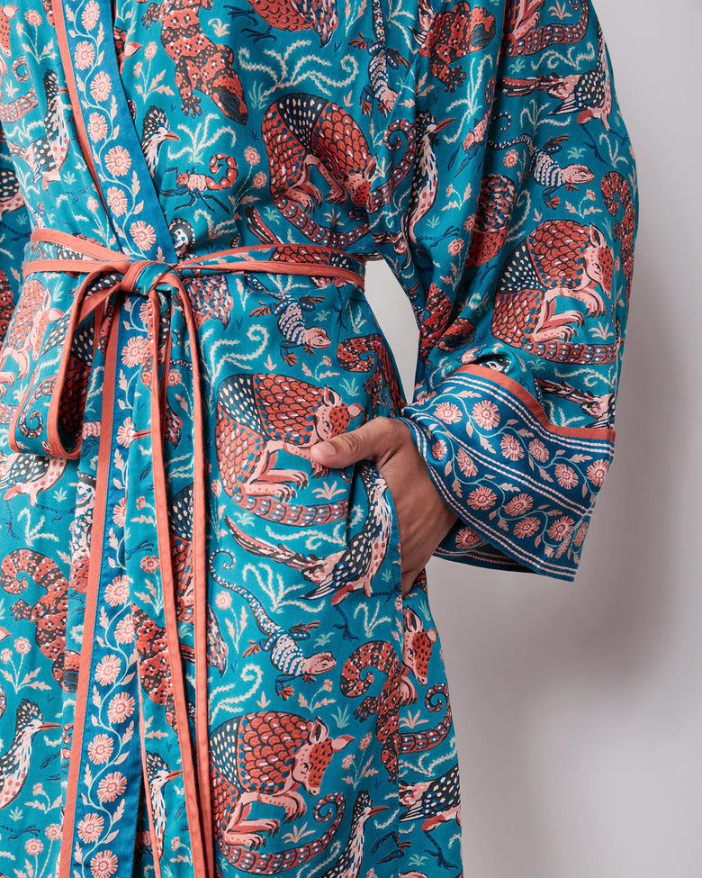 Close-up of the teal satin robe showing its tie belt, patterned trim, wide cuff, and Southwestern animal print.