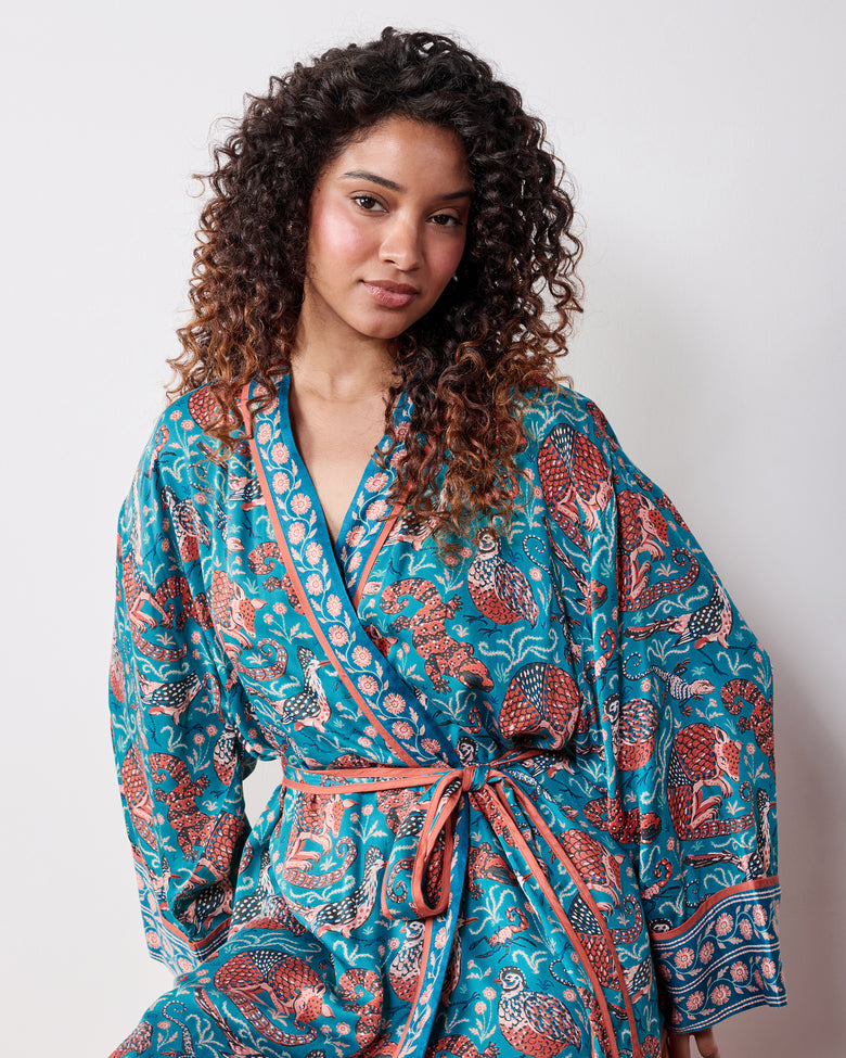 Front view of a person wearing the teal Southwestern Critters satin robe with long sleeves, a wrap front, and waist belt.