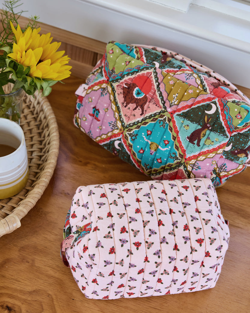 Close view of two quilted oversized pouches showing their colorful patchwork-style and floral prints.