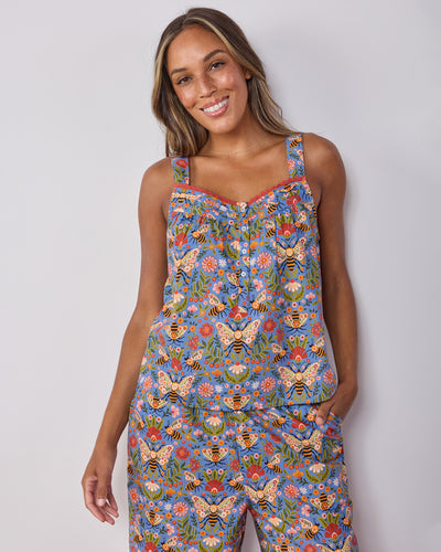 Front view of a sleeveless pajama top with shoulder straps, buttons, red trim, and a blue bee-and-floral print.