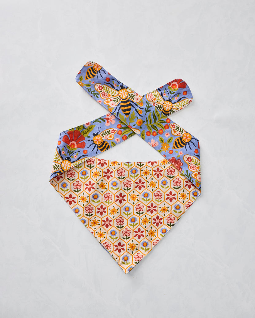 Reverse side of the Bee Tapestry pet bandana shown flat, with blue floral-and-bee straps and a cream repeating floral-patterned point.