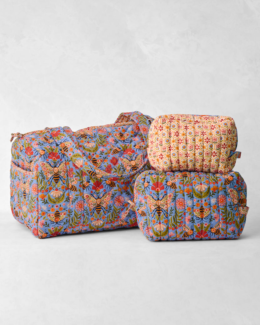 Bee Tapestry quilted duffle and two coordinating pouches, arranged together.