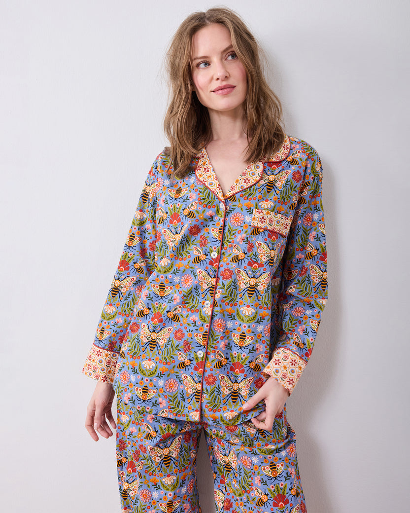 Front three-quarter view of the Bee Tapestry Delphinium Blue petite long pajama set, showing the button-down top, chest pocket, and matching printed pants.