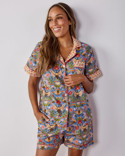 Model wearing the blue Bee Tapestry short pajama set with a button-front shirt and matching shorts.