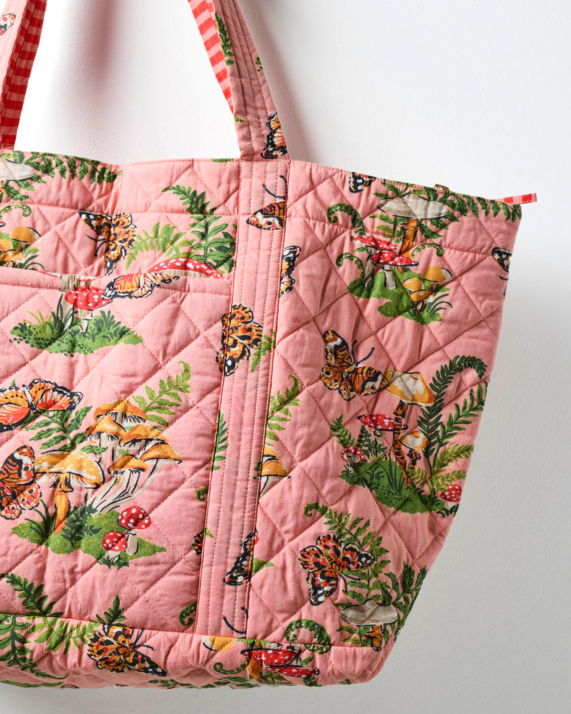Close-up of the rosewood quilted weekend bag showing diamond stitching, printed fabric, and reinforced shoulder strap.