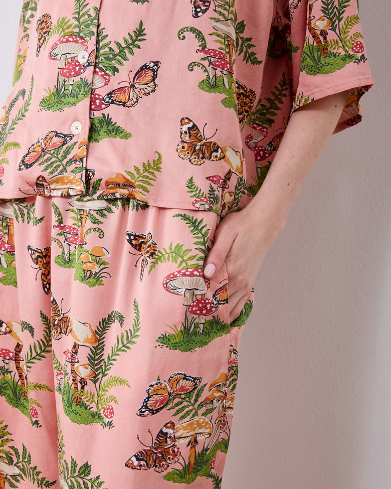 Close-up of the pink Butterfly Forager petite satin Wildest Dreams pajama set showing the button-front top and a side pocket on the wide-leg pants.