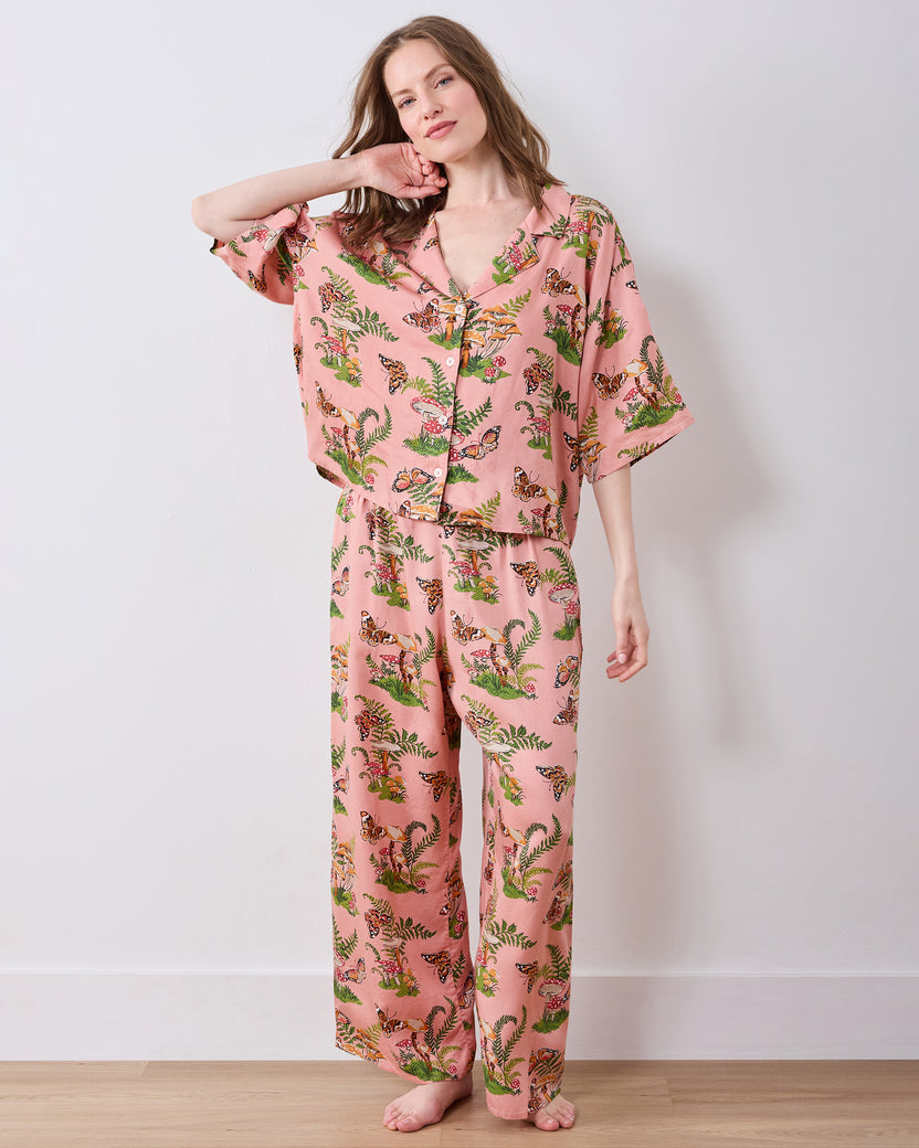 Full-length view of a person wearing a rosewood pajama set with a butterfly, mushroom, and fern print.