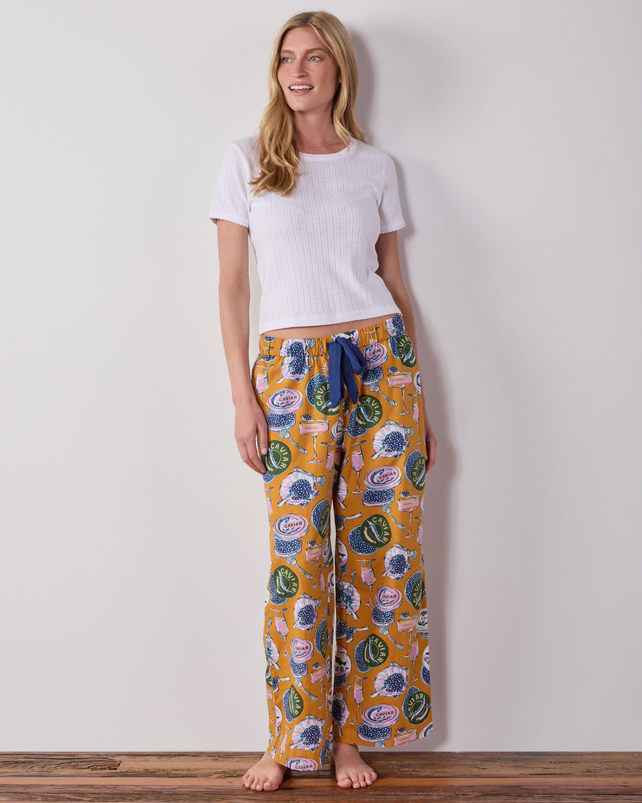 Model wearing Goldenrod Champagne & Caviar petite pajama pants with a white short-sleeved top and blue drawstring.
