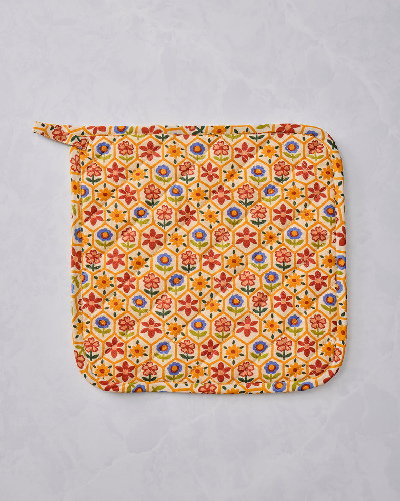 Reverse side of the Bee Tapestry pot holder shown flat with an allover cream floral pattern and a hanging loop.
