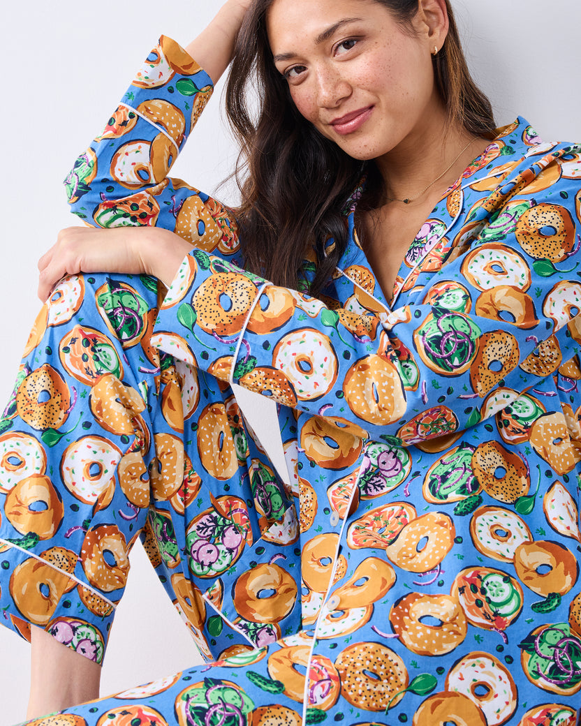 Model wearing the blue long pajama set with a print of bagels, toppings, and vegetables