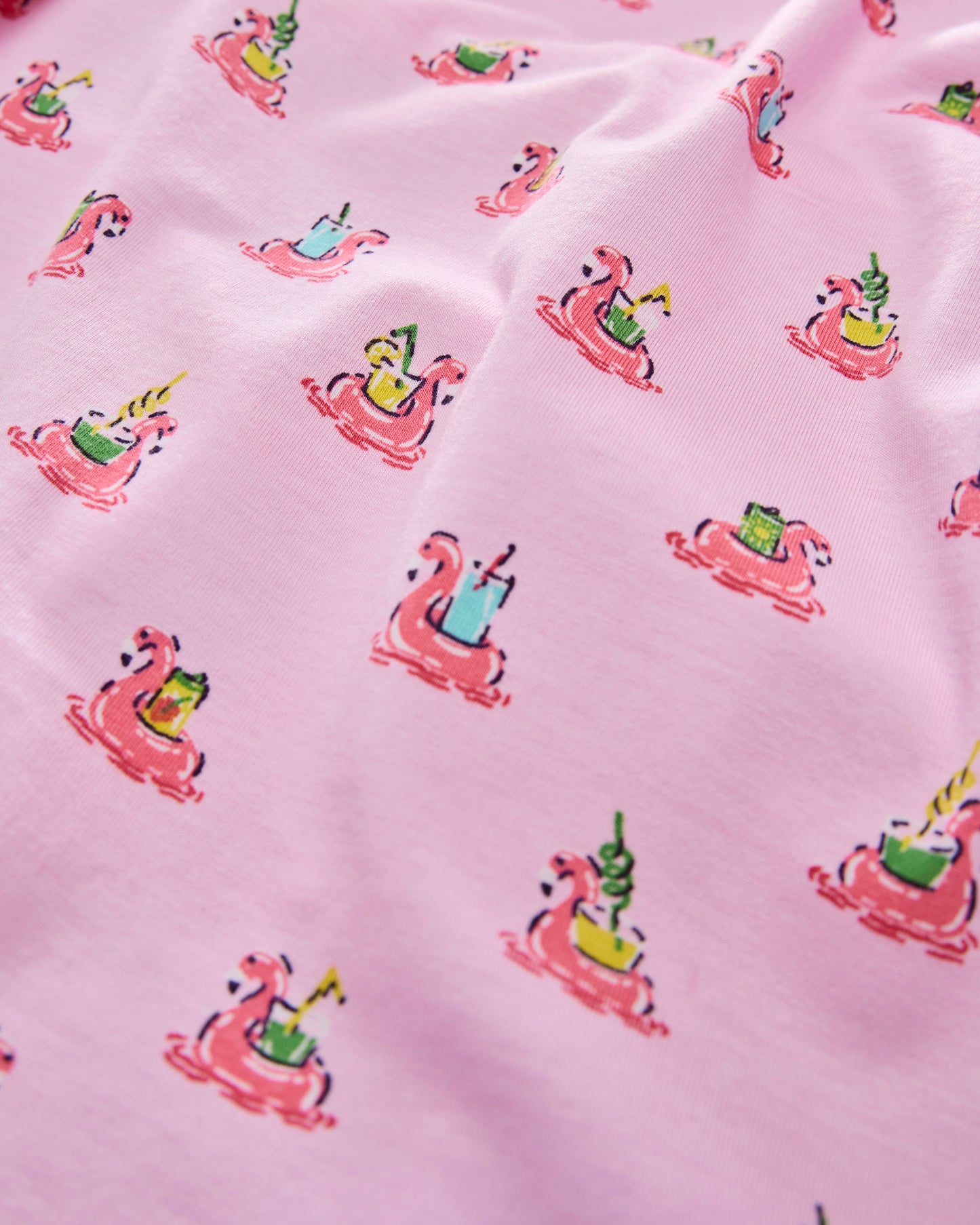 Close-up of pink fabric with flamingos floating in inner tubes and colorful drinks