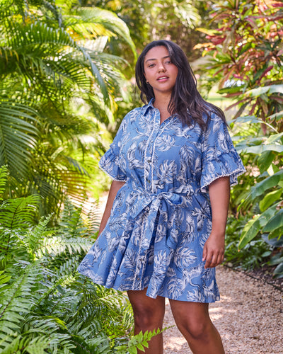 Full front view of the blue Estelle Dress with heron and leaf print, button front, ruffled sleeves, and tied belt