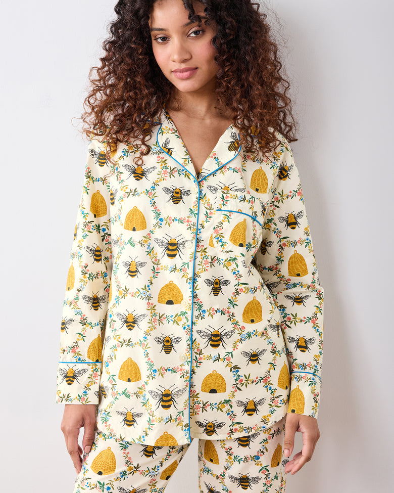 Model wearing the cream long pajama set with bees, beehives, and floral wreaths