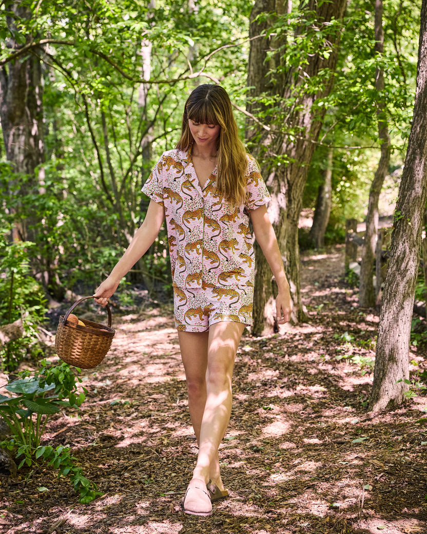 Blush Bagheera short pajama set with a button-front short-sleeve top and matching shorts, modeled on a wooded path.