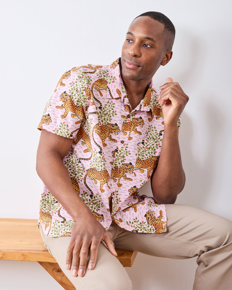 Seated front view of the blush short-sleeve button-down shirt with spotted cats and leafy branches.