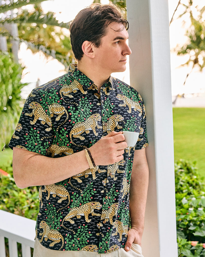 Model wearing the short-sleeve Bagheera button-down shirt and holding a cup outdoors