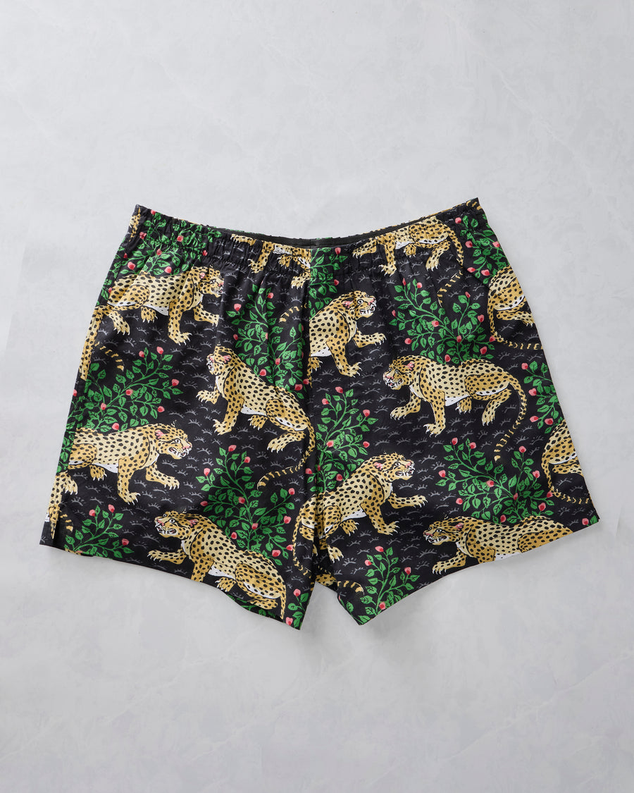 Ink boxer shorts laid flat with a spotted leopard, green foliage, and pink berry print