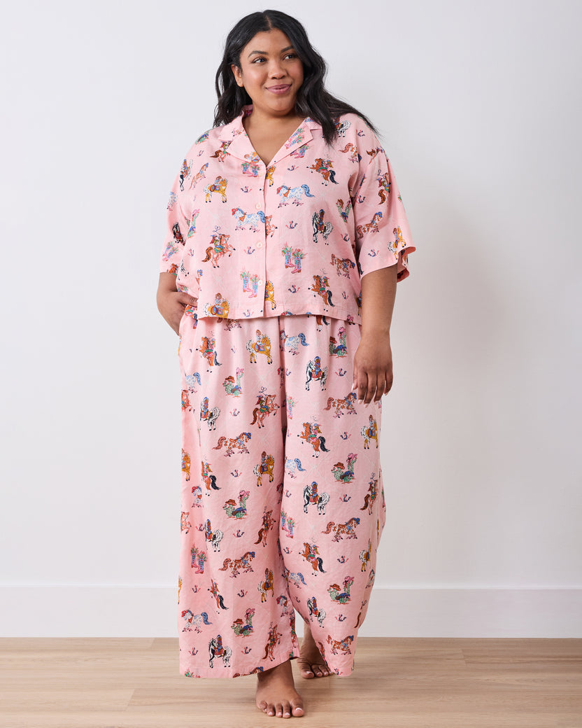 Full-length view of a model wearing the pink cowgirl-print petite pajama set with a short-sleeved top and wide-leg pants.