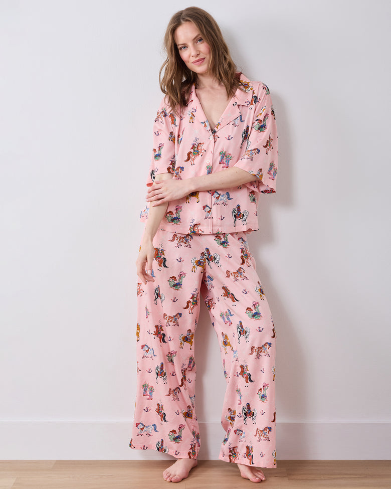 Full-length view of a pink cowgirl-print pajama set with a short-sleeved button-down top and wide-leg pants.