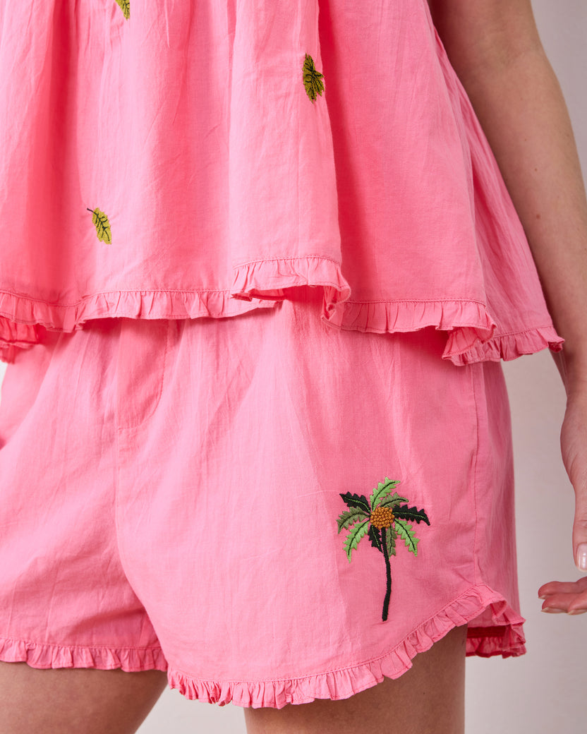 Close-up of the Coral Sunset ruffled top and flutter shorts with embroidered palm-tree details