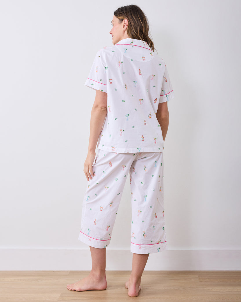 Back view of a person wearing the cloud short-sleeve pajama top and cropped pants with pink piping and embroidered cocktail-themed motifs.