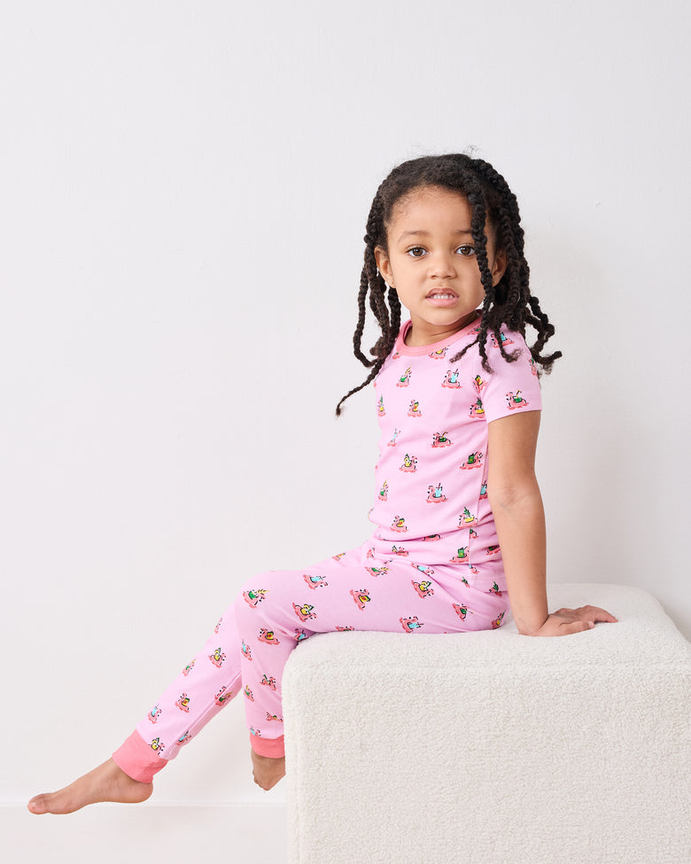 Side view of a child seated in the pink Flamingo Floaties short-sleeve pajama top and pants