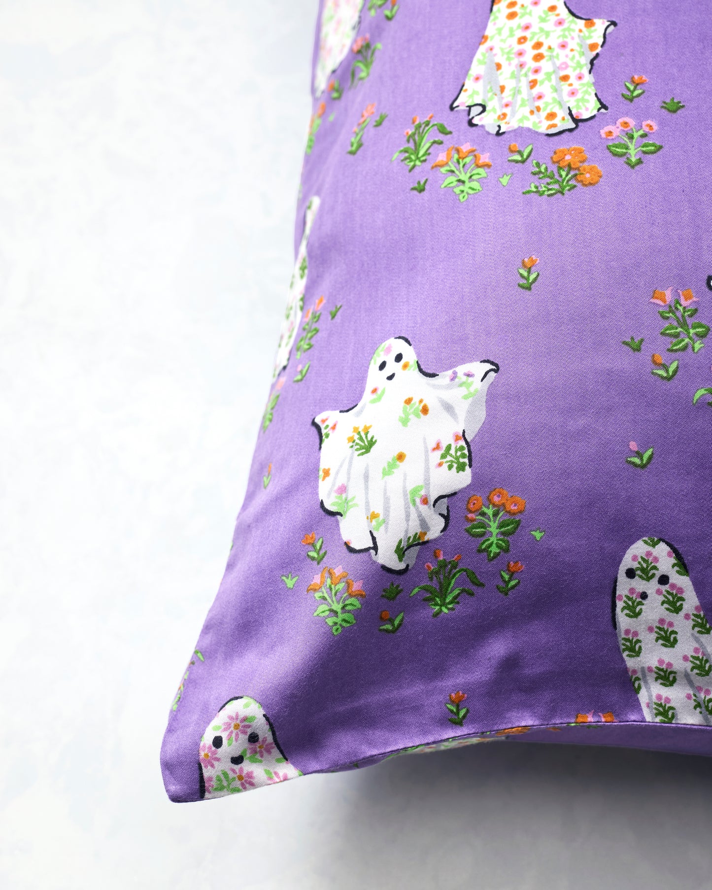 Purple Gardening Ghosts pillowcase shown close up, with white floral ghosts and scattered flowers.