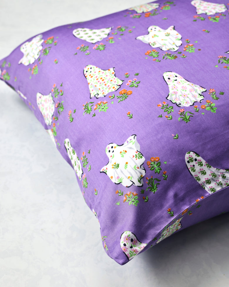 Purple Gardening Ghosts pillowcase spread out to show its repeating white ghost and floral print.