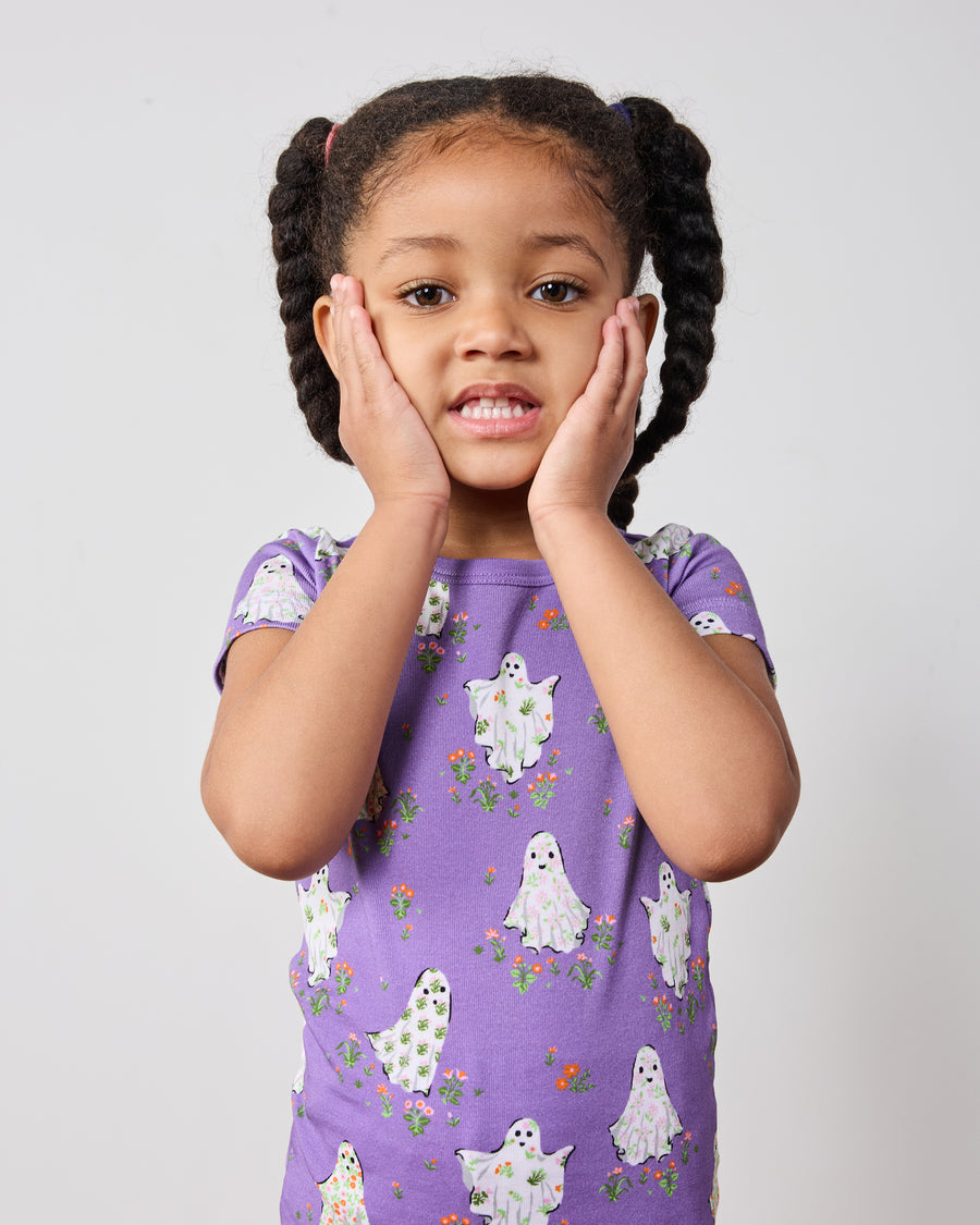 Close front view of a child wearing a purple short-sleeve ghost-print pajama top