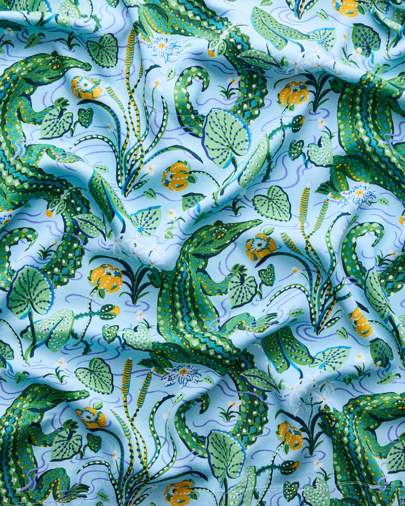 Close-up of the blue-green print with gators, leaves, flowers, and winding water lines